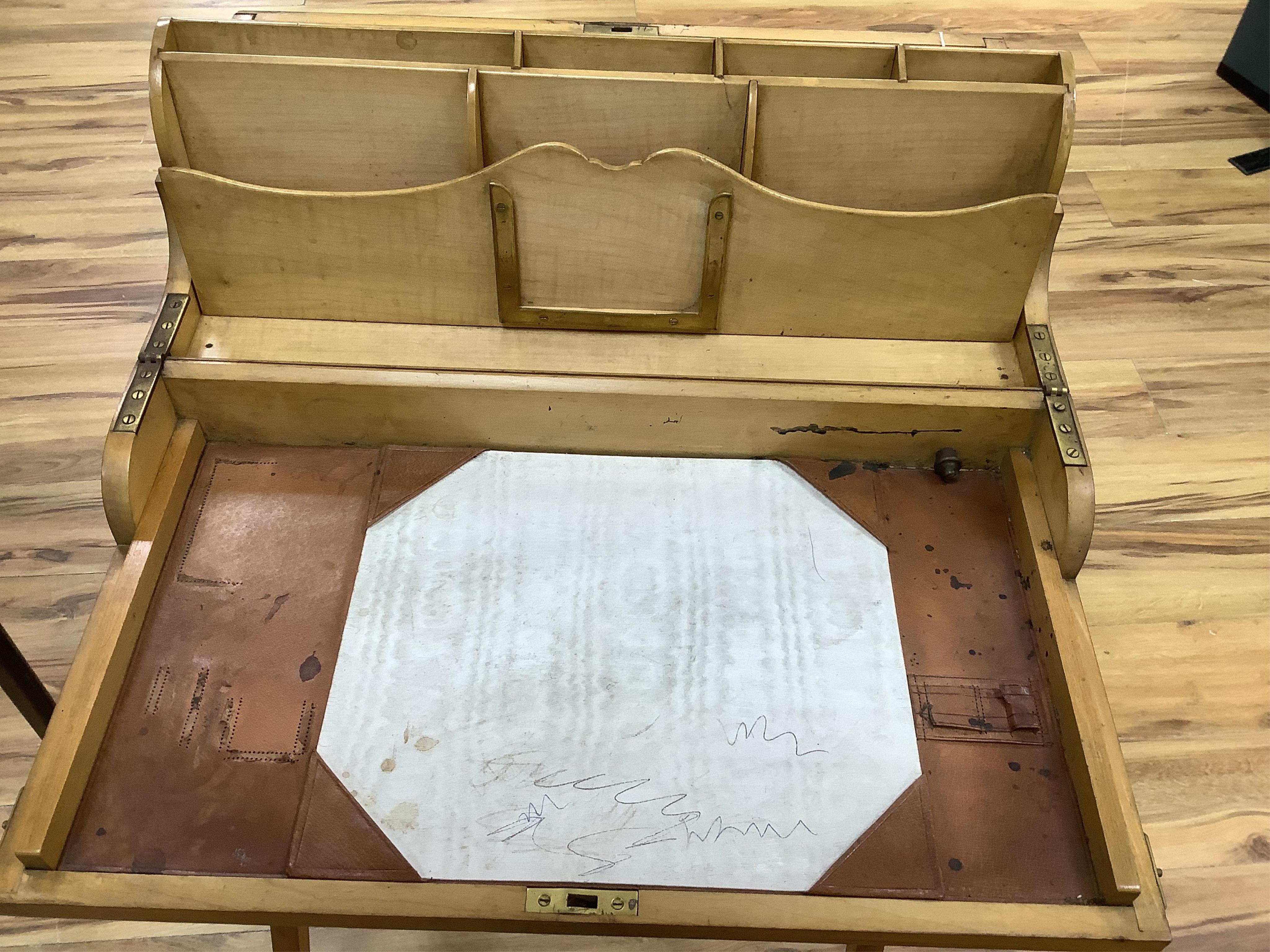 A late 19th century sycamore military folding campaign desk, raised on a trestle stand with X shaped supports, desk section with leather writing surface and folding letter rack, 93cm high, 56cm wide when folded. Conditio